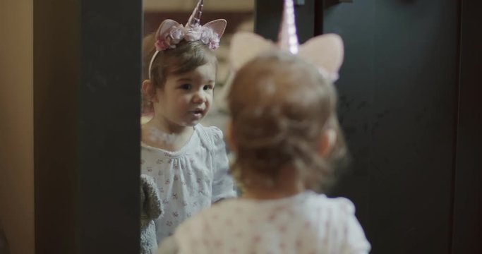 Baby girl looking at her costume in mirror. Funny, real life clip. Shot in 4K RAW on a cinema camera.