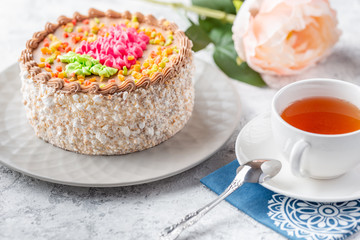 Sponge biscuite cake with cream lies on a plate. On the table are berries, a cup with tea and a spoon, a napkin.