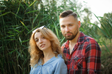 Obraz premium Close up portrait of young couple hugging and looking at the camera on green stems background, hipsters concept