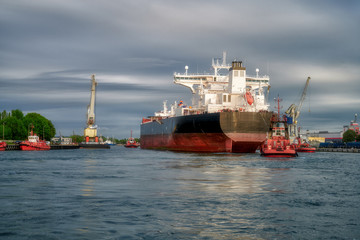 The Port of Gdansk, Poland, tugs enter the port of a large merchant ship