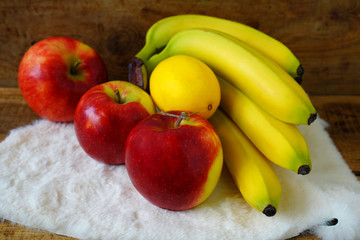 Bananas, apples and lemon on wooden table