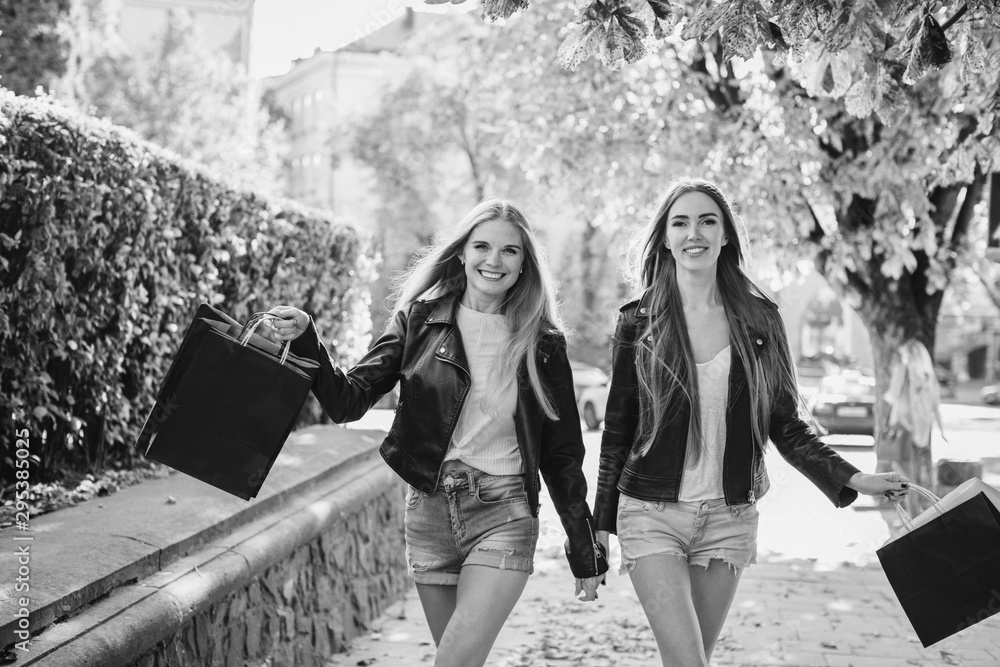 Wall mural Happy girls walking after successful shopping on Black Friday.B&W