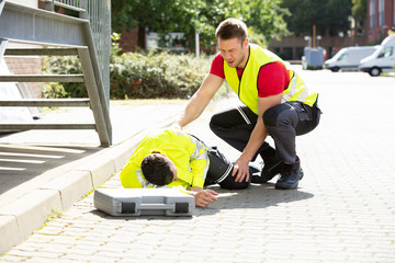 Man Wearing Safety Jacket Looking At Person Falling On Street
