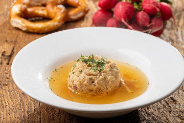 single speckknoedel in soup on wood