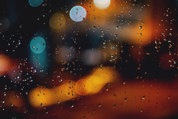 Moody dark night view of the street with rain drops on the window. View out on a cold day with...