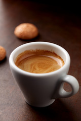Cup of coffee with amaretti (Italian biscuit) on rustic wooden background. Close up.
