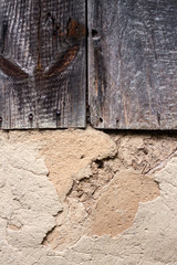 Old cob wall with cracked surface and old wooden boards