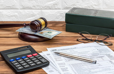 Tax forms with calculator and judge gavel at the office workplace.
