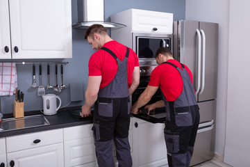 Technicians Repairing The Oven In Kitchen