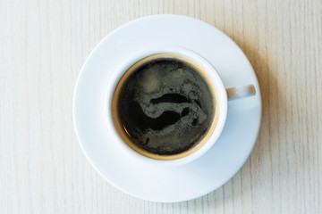 Hot black coffee in a white cup on table