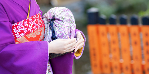 Maiko's hands holding the traditional bag