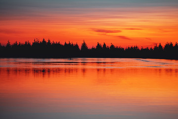 Beautiful sunset color tones in the mountains. Lake with pine tree silhouette and water reflections. Calm idyllic and peaceful place to enjoy mountains. Wurmberg, Braunlage Harz National Park