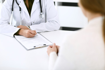 Woman doctor and patient sitting and talking at medical examination at hospital office, close-up....