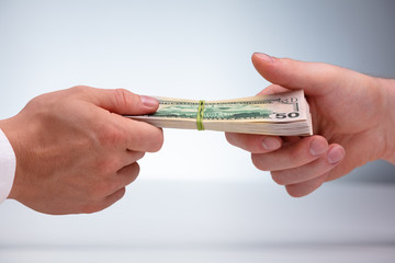 Close-up Of Two Male Hand's Holding Currency Bundle