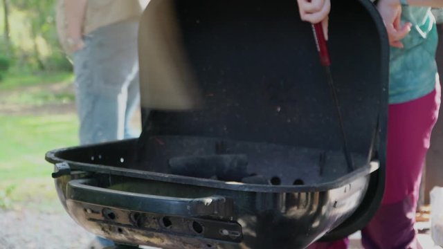 In a barbecue fan fanning the fire with the poker and adjusting the coal