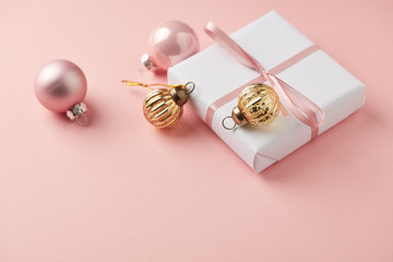 Christmas baubles and Christmas present. Pink paper background. Close up. Copy space. 