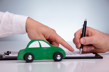 Person Buying A New Car Signing The Contract On Paper