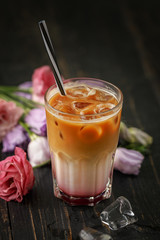 A glass of coffee drink on a slate black plate with a slice of cake, berries and mint.