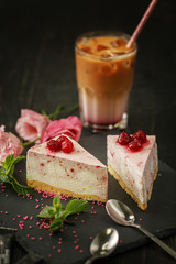 A glass of coffee drink on a slate black plate with a slice of cake, berries and mint.