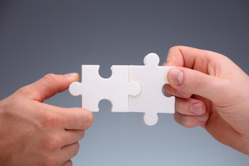 Two People Joining The Jigsaw Puzzles