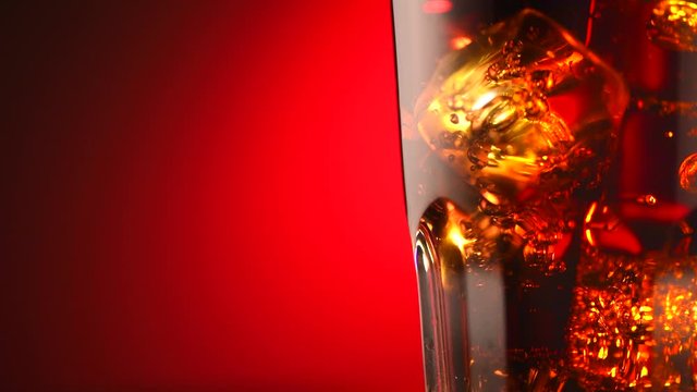 Coke with ice cubes closeup. Glass of fizzy cola rotated over red background. 4K UHD video footage. 3840X2160