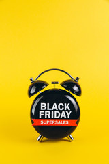 Black Friday concept. Alarm clock on yellow background.