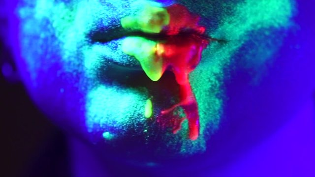 Fashion model woman in neon light, beautiful model girl lips with colorful bright fluorescent makeup. Slow motion. 3840X2160 4K UHD video footage