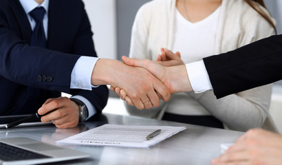 Business people shaking hands after contract signing at the glass desk in modern office. Unknown businessman, male entrepreneur with colleagues at meeting or negotiation. Teamwork, partnership and