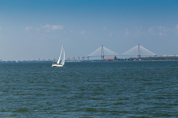 Sailboat in Charleston SC Harbor with Cooper River Bridge and Yacht Slips of Patriots Point Naval Museum