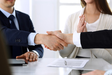 Business people shaking hands after contract signing at the glass desk in modern office. Unknown businessman, male entrepreneur with colleagues at meeting or negotiation. Teamwork, partnership and