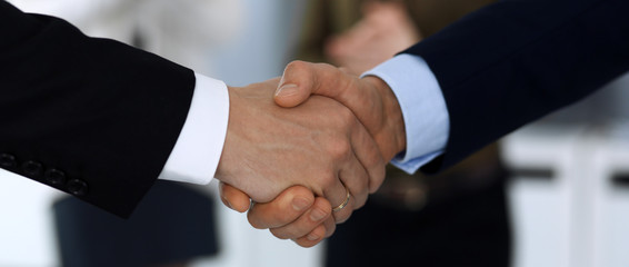 Business people shaking hands after contract signing in modern office. Unknown businessman, male entrepreneur with colleagues at meeting or negotiation. Teamwork, partnership and handshake concept