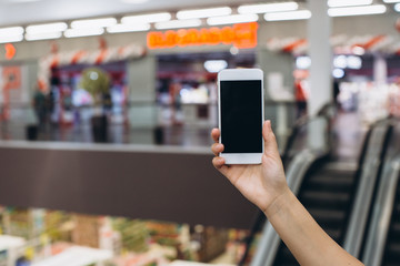 Hand using smartphone for doing business or banking or buying online on blur shopping mall background