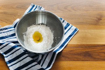 egg in flour at a metal bowl with brown background