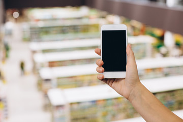Hand using smartphone for doing business or banking or buying online on blur shopping mall background