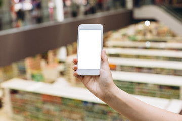 Hand using smartphone for doing business or banking or buying online on blur shopping mall background