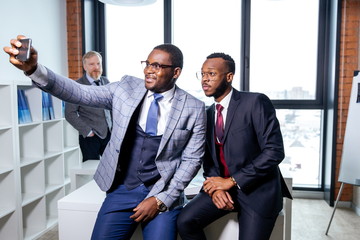 Two African businessmen take selfies in new office