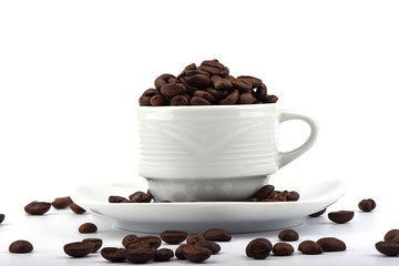 A cup full of coffee beans on a saucer over a white background.