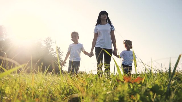 happy family funny walking go for are hold hands a teamwork Silhouette. happy children little boy and girl with mother family at sunset. mom and son mom lifestyle daughter and son in white t-shirts