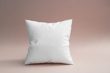 Fototapeta na wymiar White pillow against gray-pink backdrop.