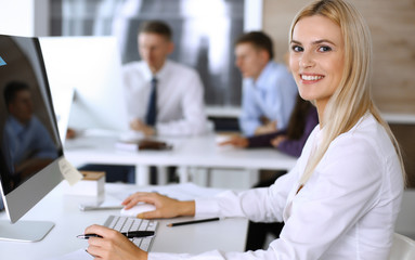 Business woman using computer at workplace in modern office. Secretary or female lawyer smiling and looks happy. Working for pleasure and success