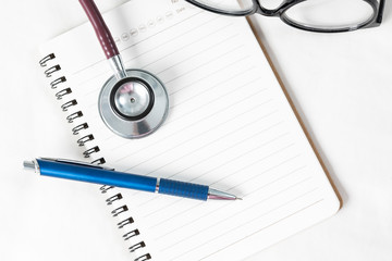 Stethoscope with blank note book on dotor table
