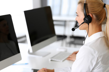 Call center. Happy and excited business woman using headset while consulting clients online....