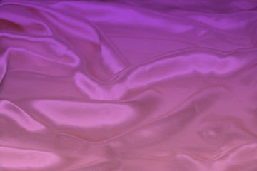 beautiful luxury texture of silk draped fabric with tints of pink, purple, top view, close-up, copy space