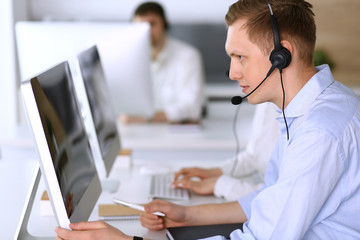 Call center. Group of diverse operators at work. Focus on businessman in headset at customer service office. Business concept