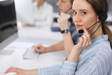 Call center. Group of casual dressed operators at work. Focus on business woman in headset at customer service office. Telesales in business