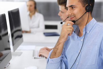 Call center. Group of casual dressed operators at work. Focus on adult businessman in headset at customer service office. Telesales in business