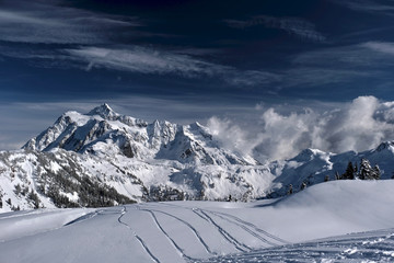 Ski tracks on fresh snow with a beautiful view of mountains in Mount Baker ski area. Fresh snow on Artist Point after snowfall. Winter landscape in North Cascades Mountains. Washington. USA