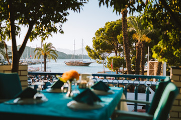 A Turkish dinner table set with the harbour, yachts and traditional gulets in the background. Fethiye dock, Turkey.  - obrazy, fototapety, plakaty
