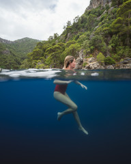 Beautiful young girl swimming peacefully in the clear blue waters of the Turkish Mediterranean sea. 