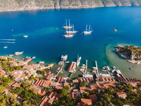 Aerial drone perspective of luxury Turkish gulets and yachts in the deep blue and turquoise waters of the mediterranean sea. The bay and cliffs protect the boats from the strong winds.
